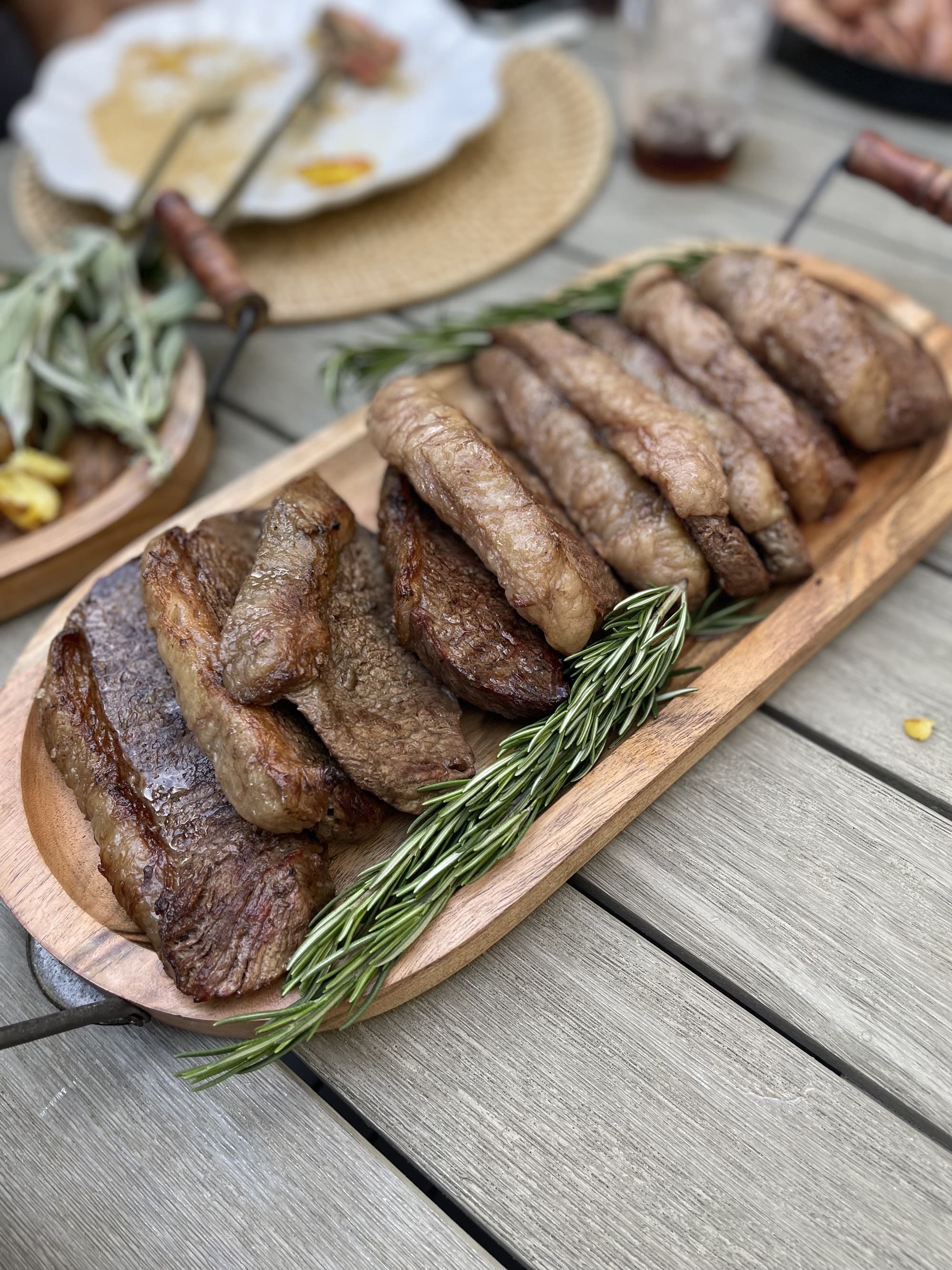 Sliced picanha from a live-fire cook on a wood board by a private chef in Austin