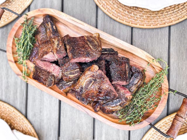 A wood board of grilled ribs and meats by a private chef for a dinner party in Dallas
