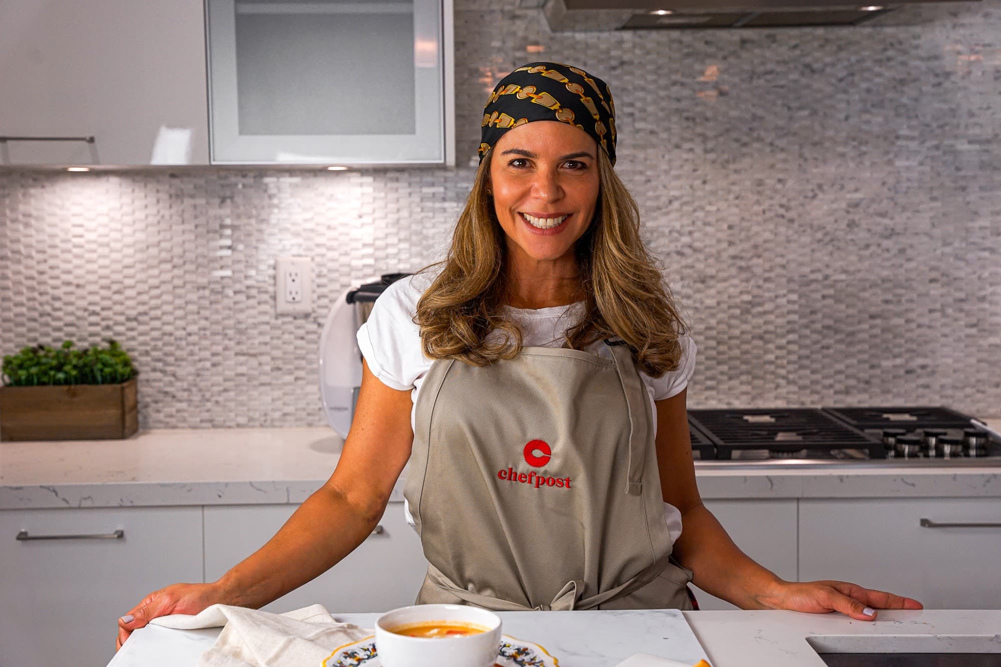 A Chefpost chef in an apron standing at a home kitchen counter