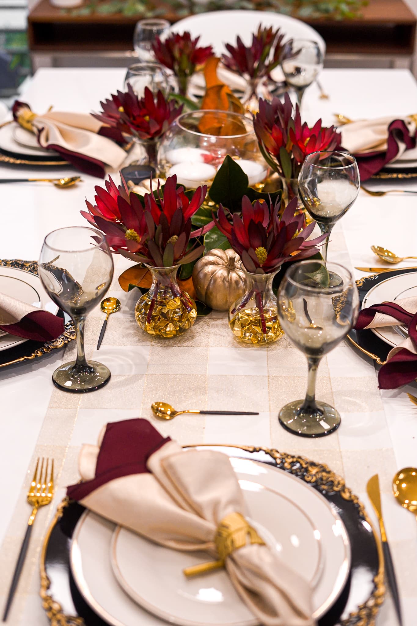 An elegant dinner-party table with burgundy florals and gold accents set by a private chef