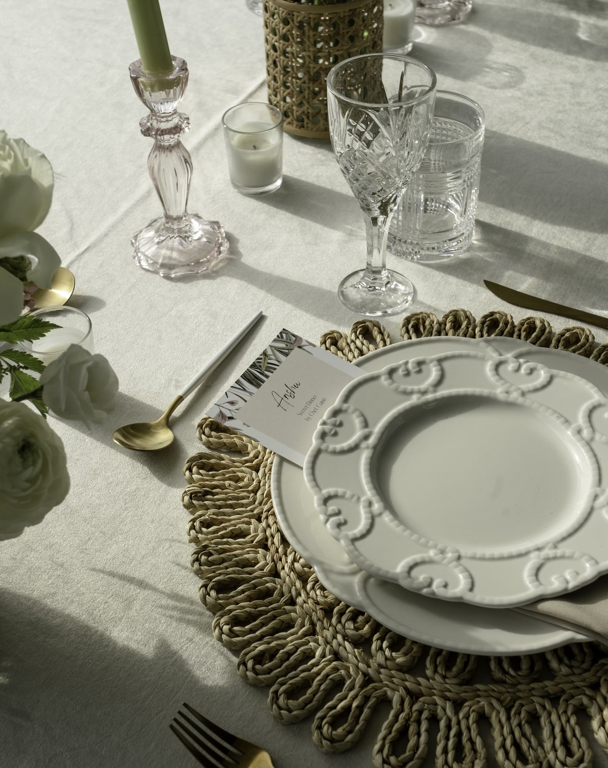 An elegant neutral place setting with a fringed placemat and gold cutlery for a private chef dinner in Short Hills