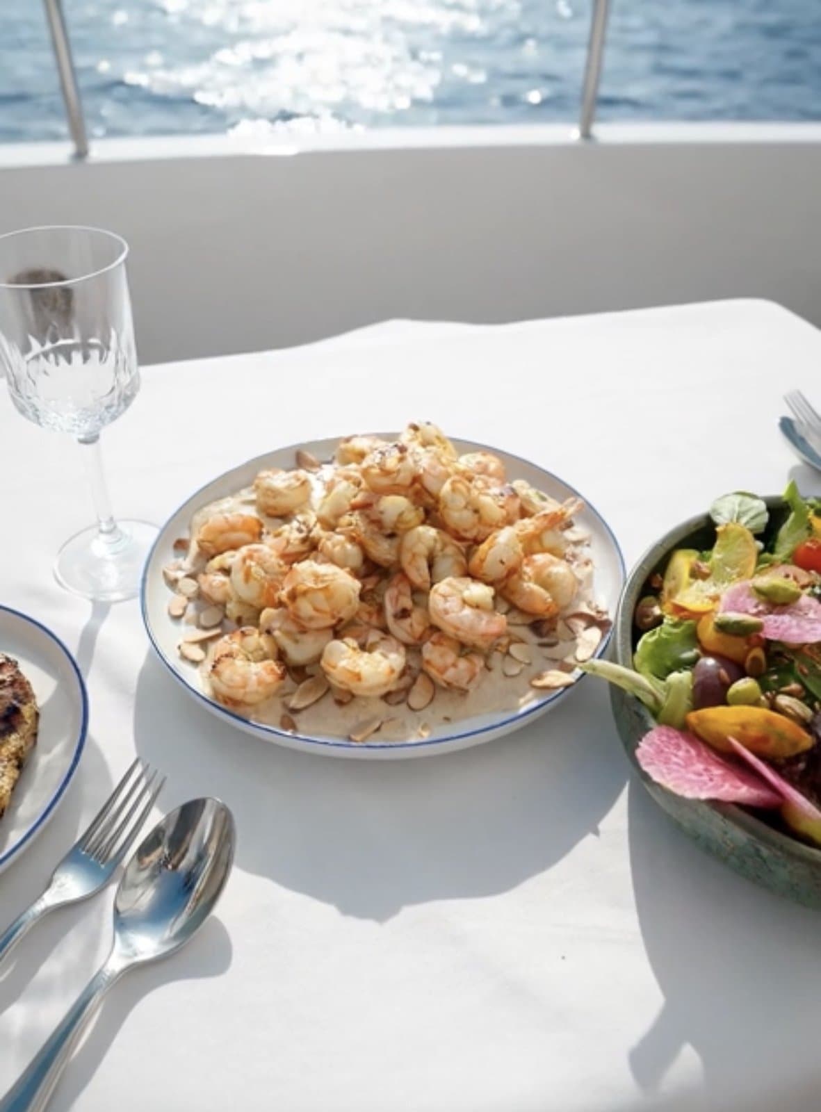Grilled shrimp platter and a fresh salad served on a yacht table