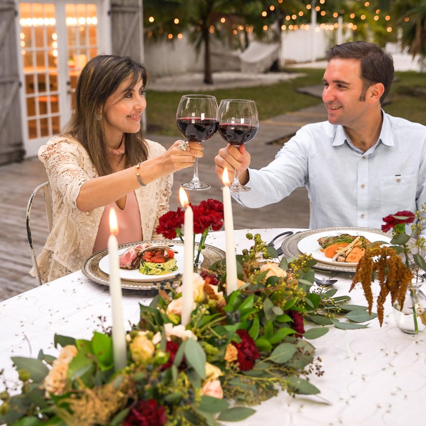 Couple toasting with red wine at a private chef dinner at home