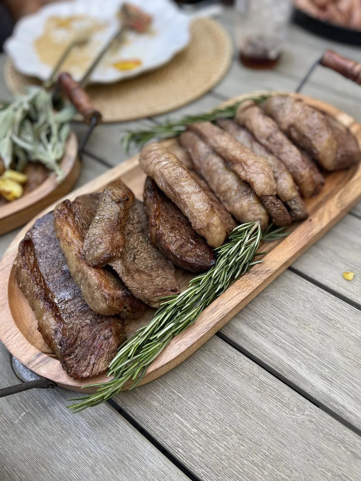 Sliced picanha from a live-fire cook on a wood board by a private chef in Austin